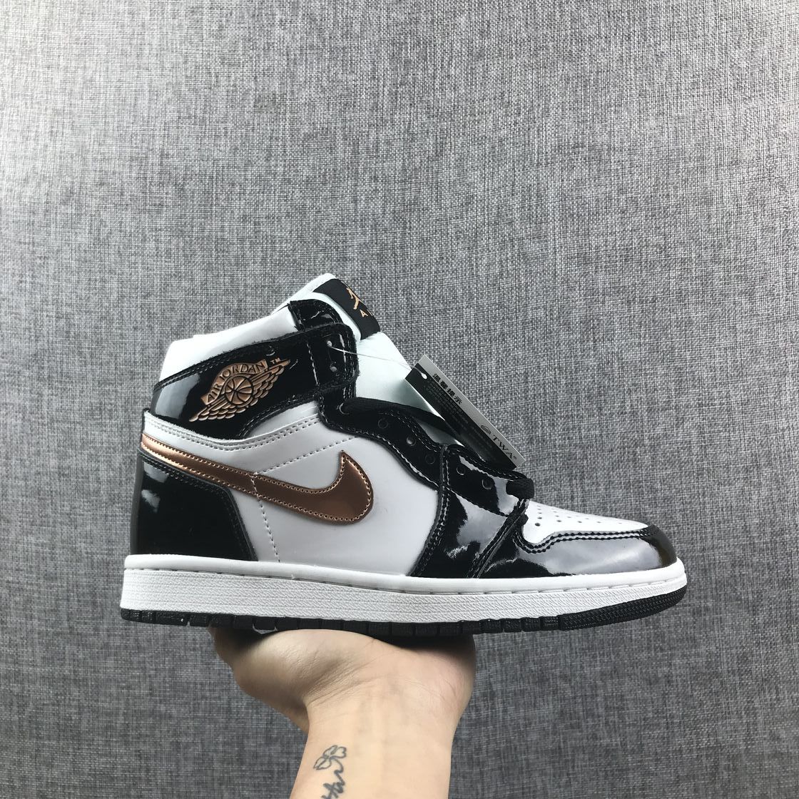 Side view of a black, white and metallic-gold Air Jordan 1 Mid sneaker held against a gray fabric background.