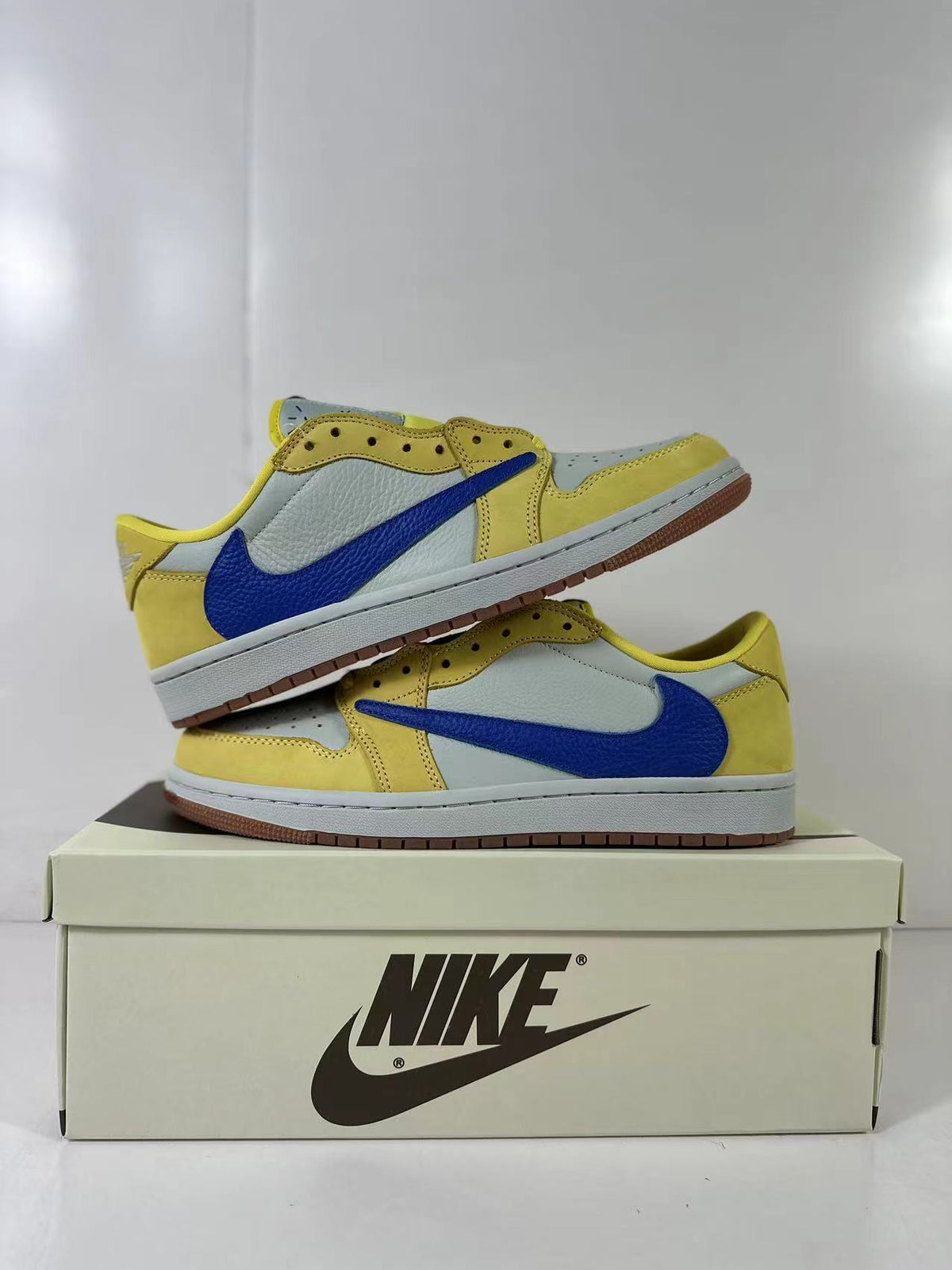 Pair of yellow, light blue and blue low-top sneakers stacked on a shoebox.
