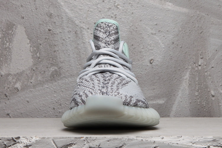 Front view of the gray and white sneaker showing its laces, patterned toe box, and rounded translucent outsole.