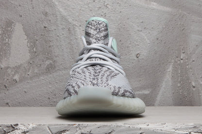 Front view of the gray and white sneaker showing its laces, patterned toe box, and rounded translucent outsole.