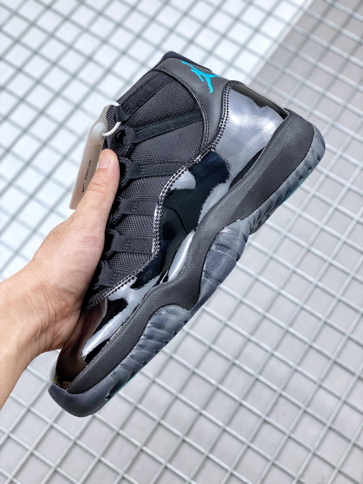 Side view of the black sneaker showing its glossy panel, textured upper and dark layered sole.