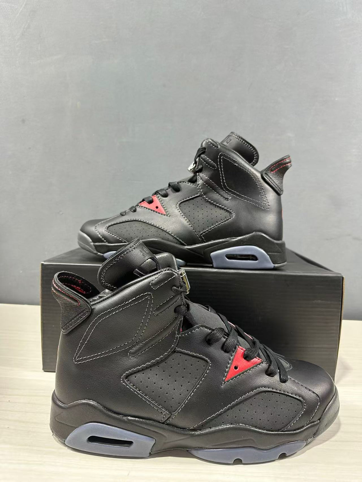 Side view showing the black upper, perforated panels, red lace-area accent, and translucent gray midsole section.