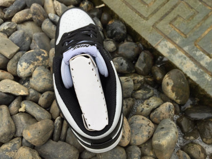 Top view of a black and white high-top sneaker showing the perforated white toe box, black laces, and padded collar.