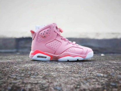 Side view of a pink Jordan Air Jordan 6 high-top sneaker with perforated panels and red midsole accents.