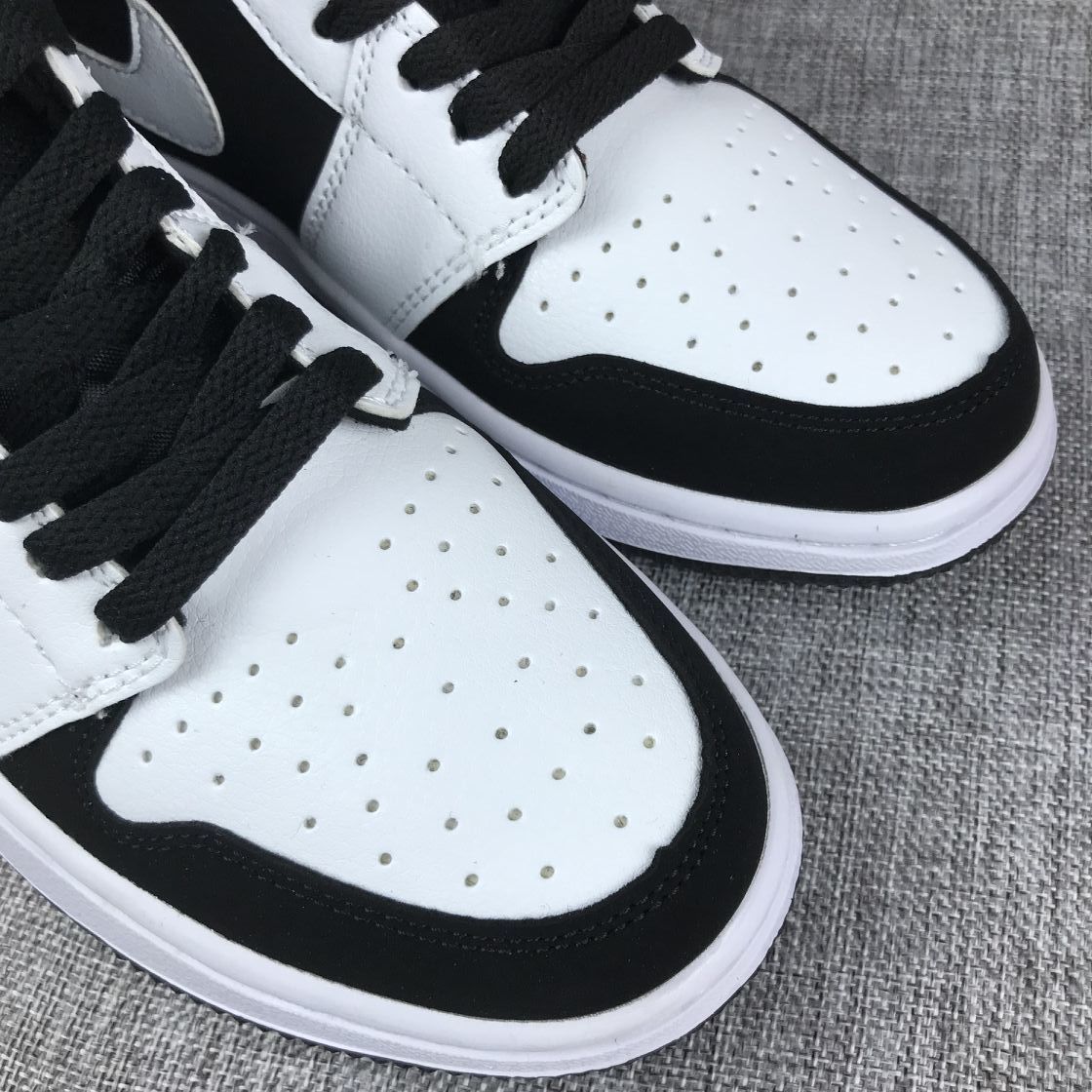 Close-up of the white perforated toe box, black toe overlay, and black laces.
