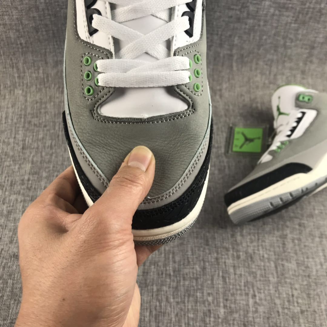 Close-up of the gray toe box, white laces, green eyelets, and black textured toe overlay.