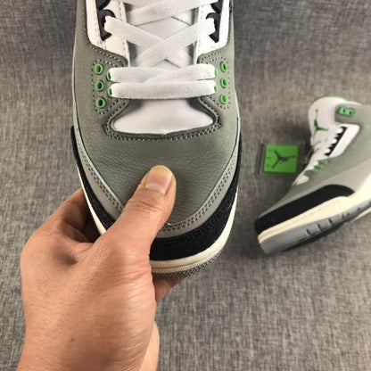 Close-up of the gray toe box, white laces, green eyelets, and black textured toe overlay.