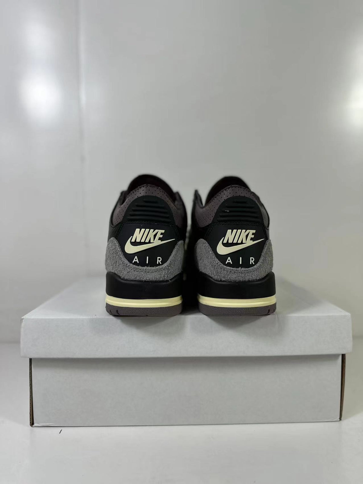 Rear view showing Nike Air branding, gray heel overlays, black heel panels, and cream midsole accents.