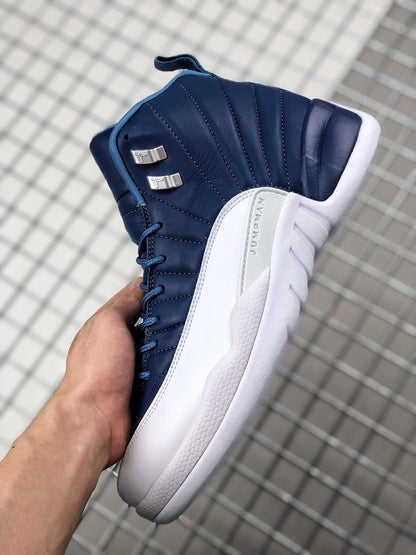 Side view of an indigo and white Jordan Air Jordan 12 sneaker showing stitched upper panels, metallic lace hardware, and a white midsole.