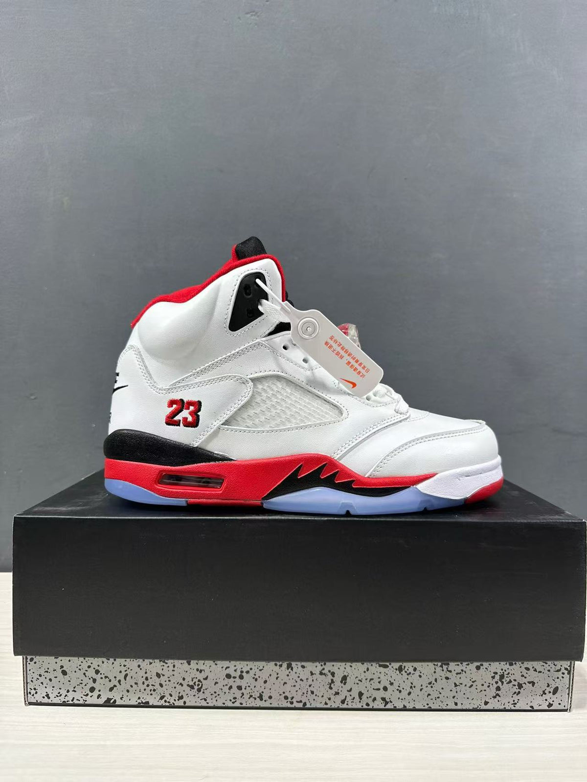 Side profile of a single white, red, and black high-top sneaker displayed on a box.
