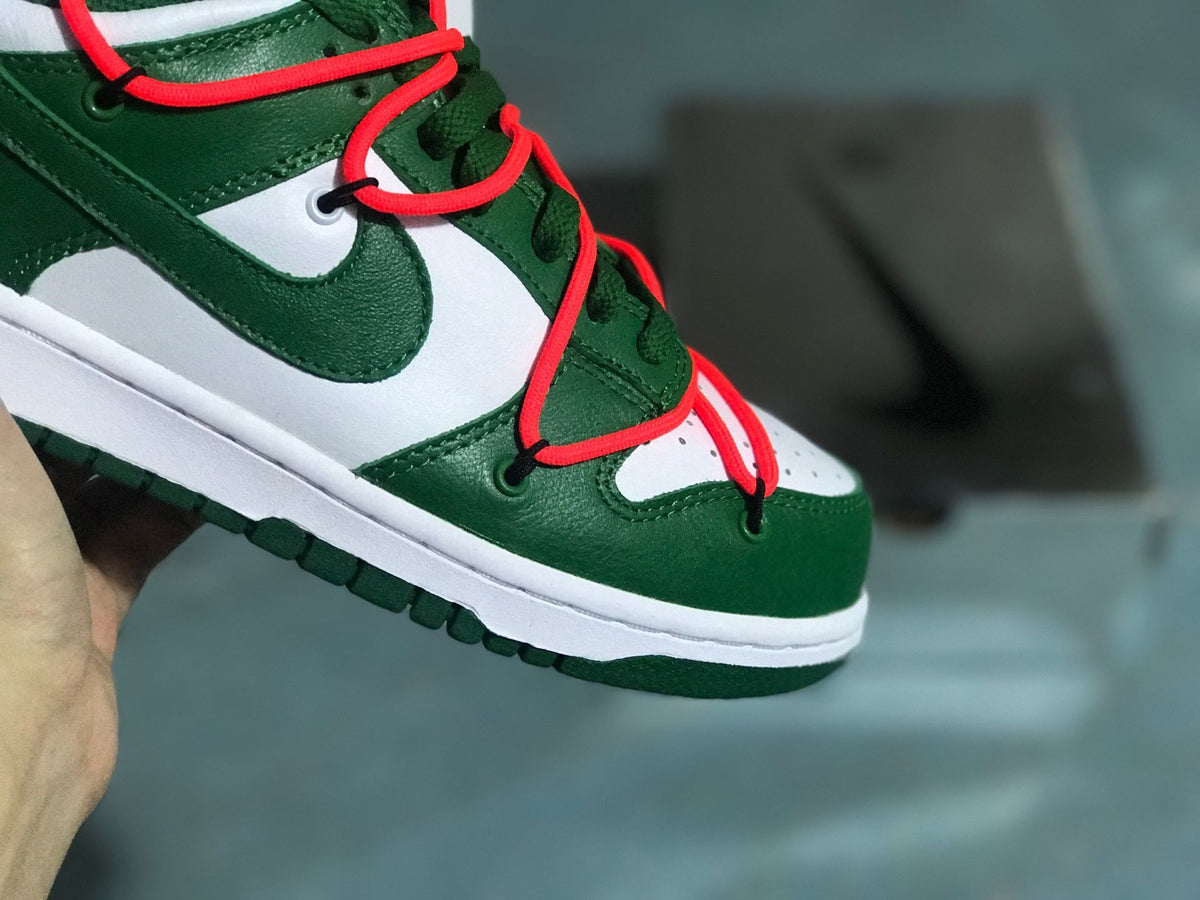 Close-up of the perforated white toe box, green toe overlay, and red lacing detail.
