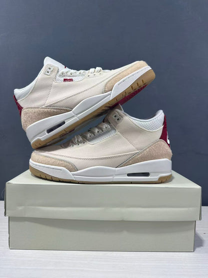 Pair of cream and red Air Jordan 3 Retro sneakers displayed in opposite directions on a shoebox.