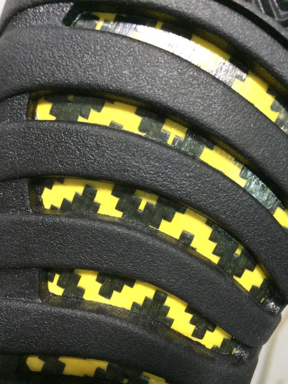 Close-up of the outsole showing yellow and black patterned sections between the black tread bands.
