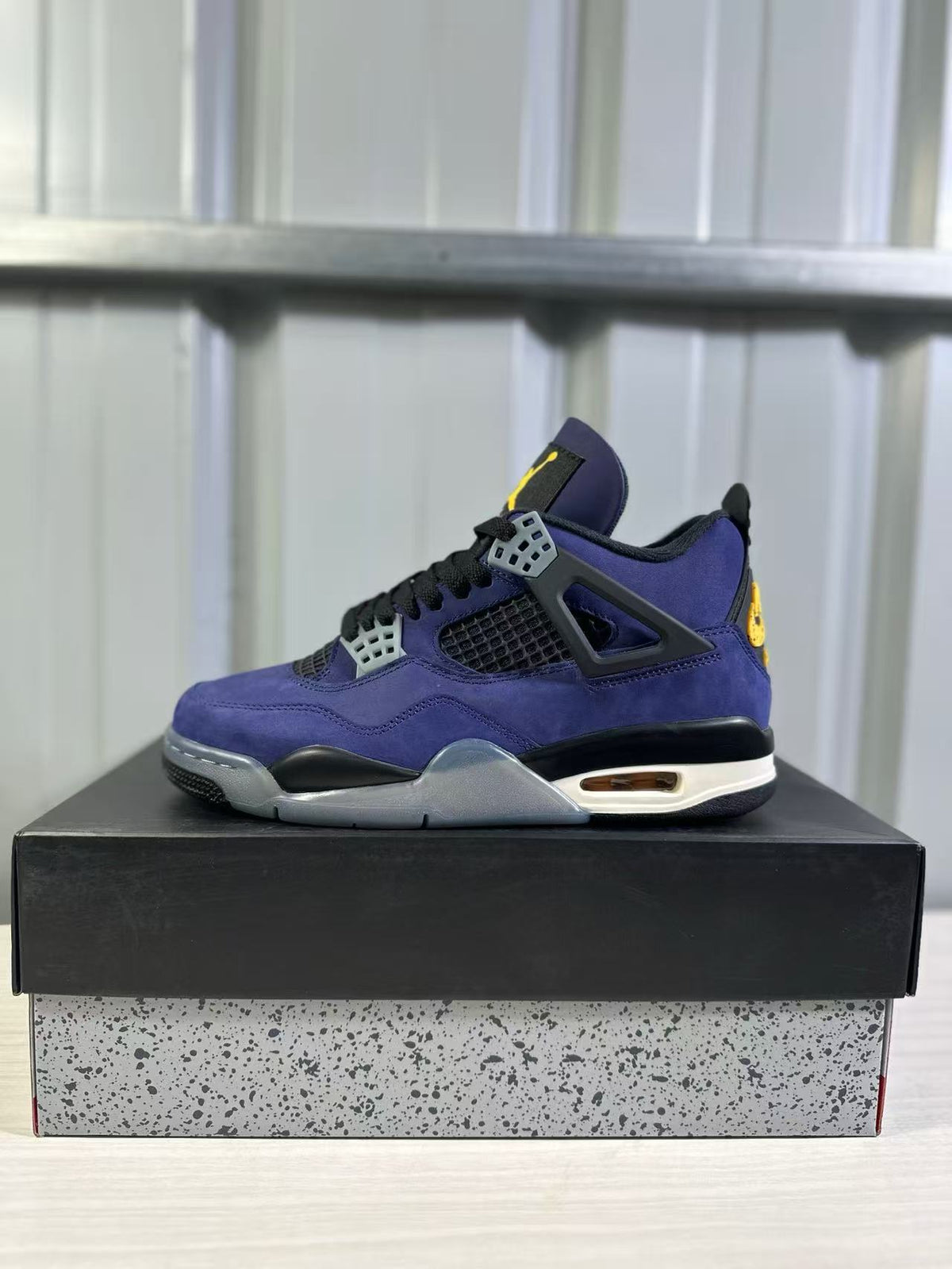 Side profile of a purple Jordan Air Jordan 4 sneaker with black laces, grey lace supports, and a cream midsole accent.