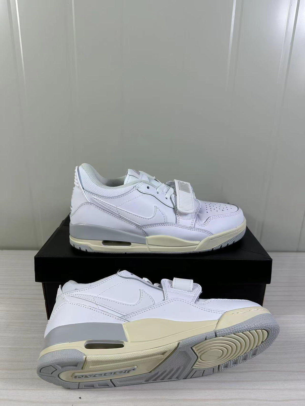 Two white sneakers displayed from side and outsole angles, highlighting the layered construction and traction pattern.