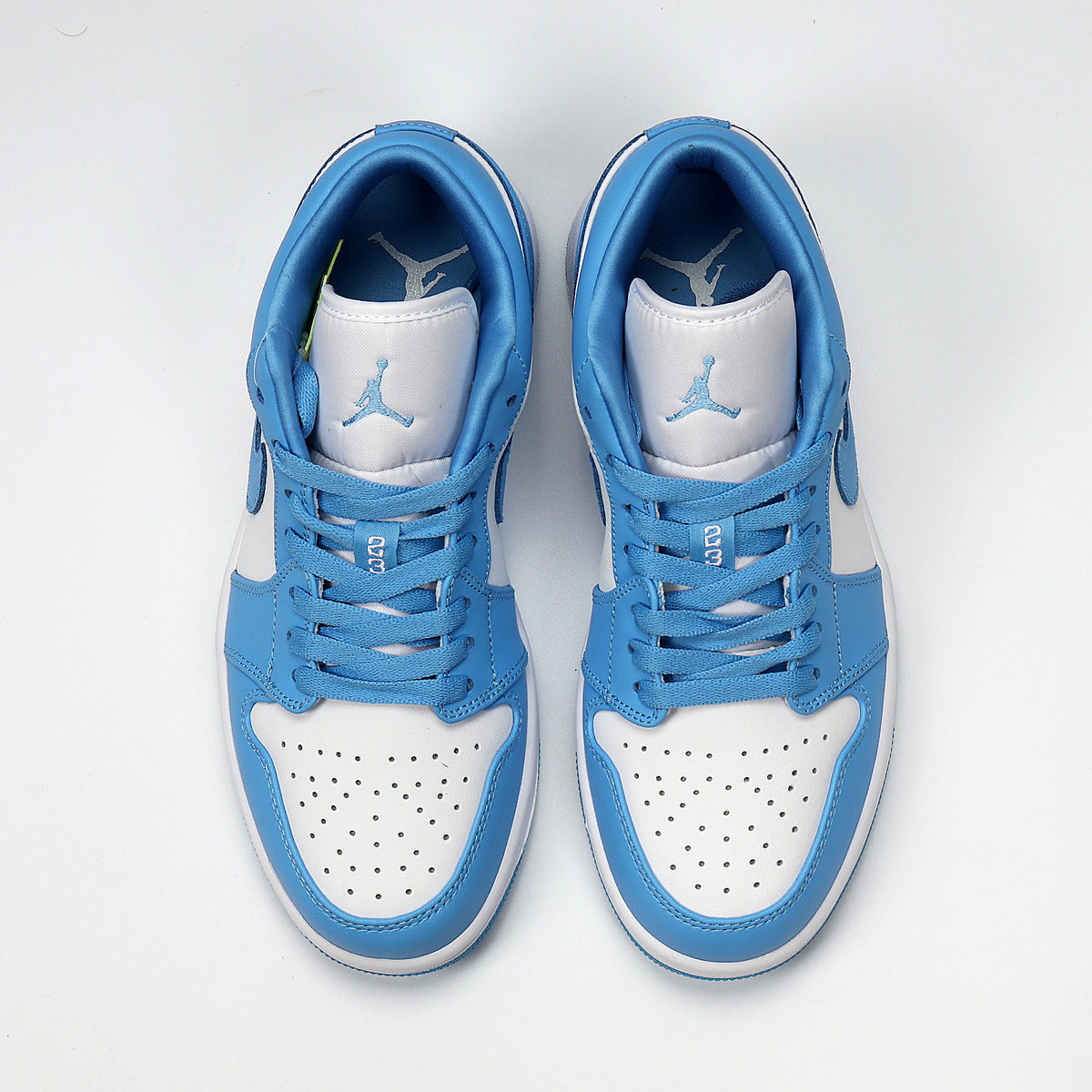 Top view of the blue and white low-top sneaker pair with perforated toe boxes and blue laces.