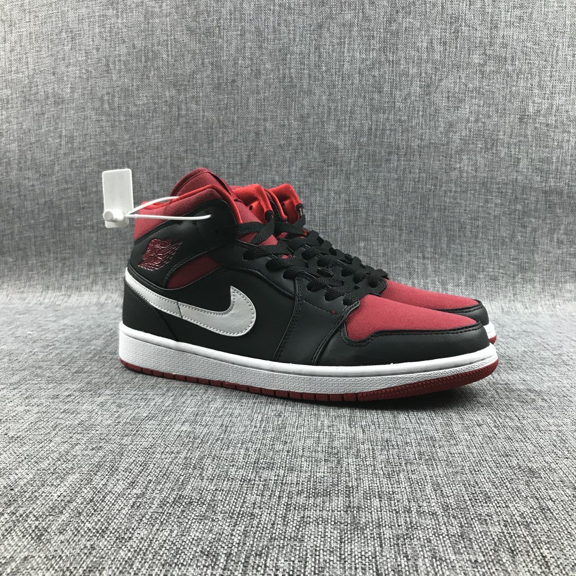 Low front-side view of the pair showing the mid-top shape, black laces, red toe panels, and red outsoles.
