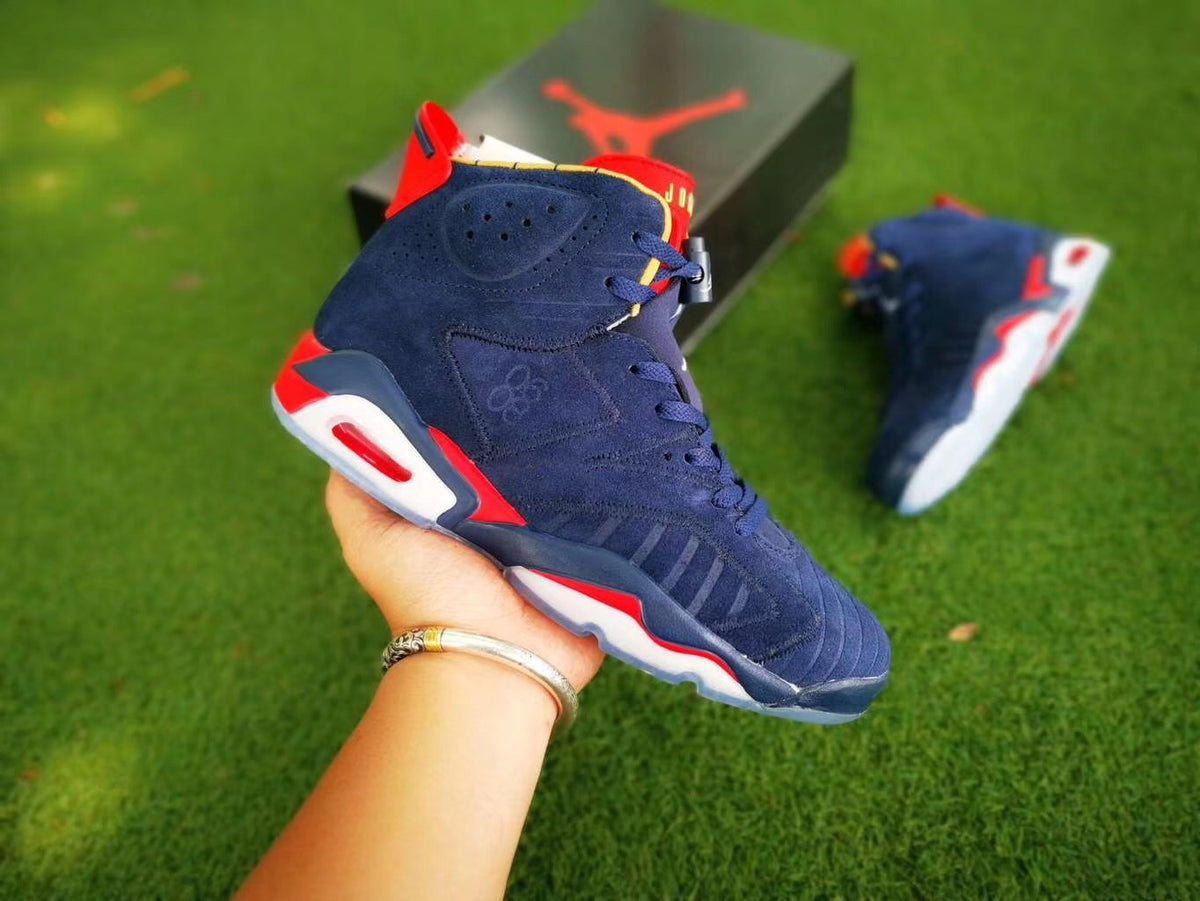 Close-up view of a navy Air Jordan 6 sneaker with red and white accents, shown beside its shoebox.