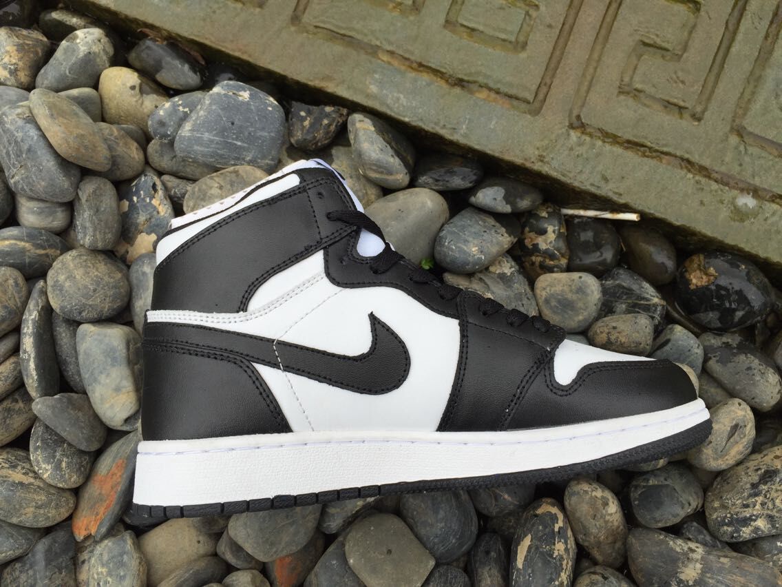 Side view showing the black and white layered upper, side swoosh-shaped emblem, white midsole, and black outsole.