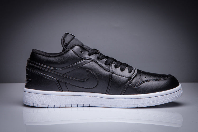 Side profile of a black low-top Jordan sneaker with a white sole on a dark studio background.