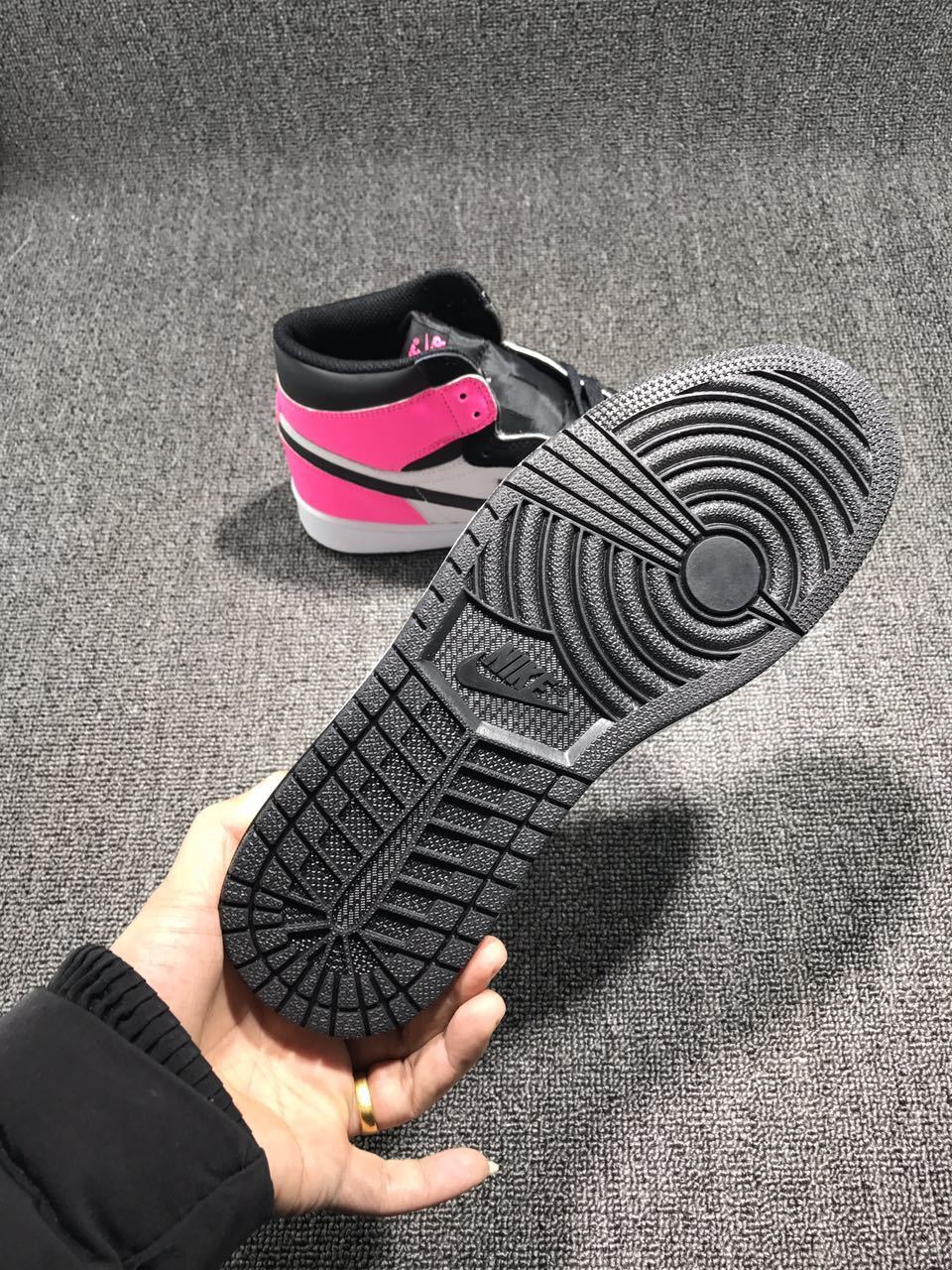 Pink, black, and white high-top sneaker shown from the outsole and rear angle.