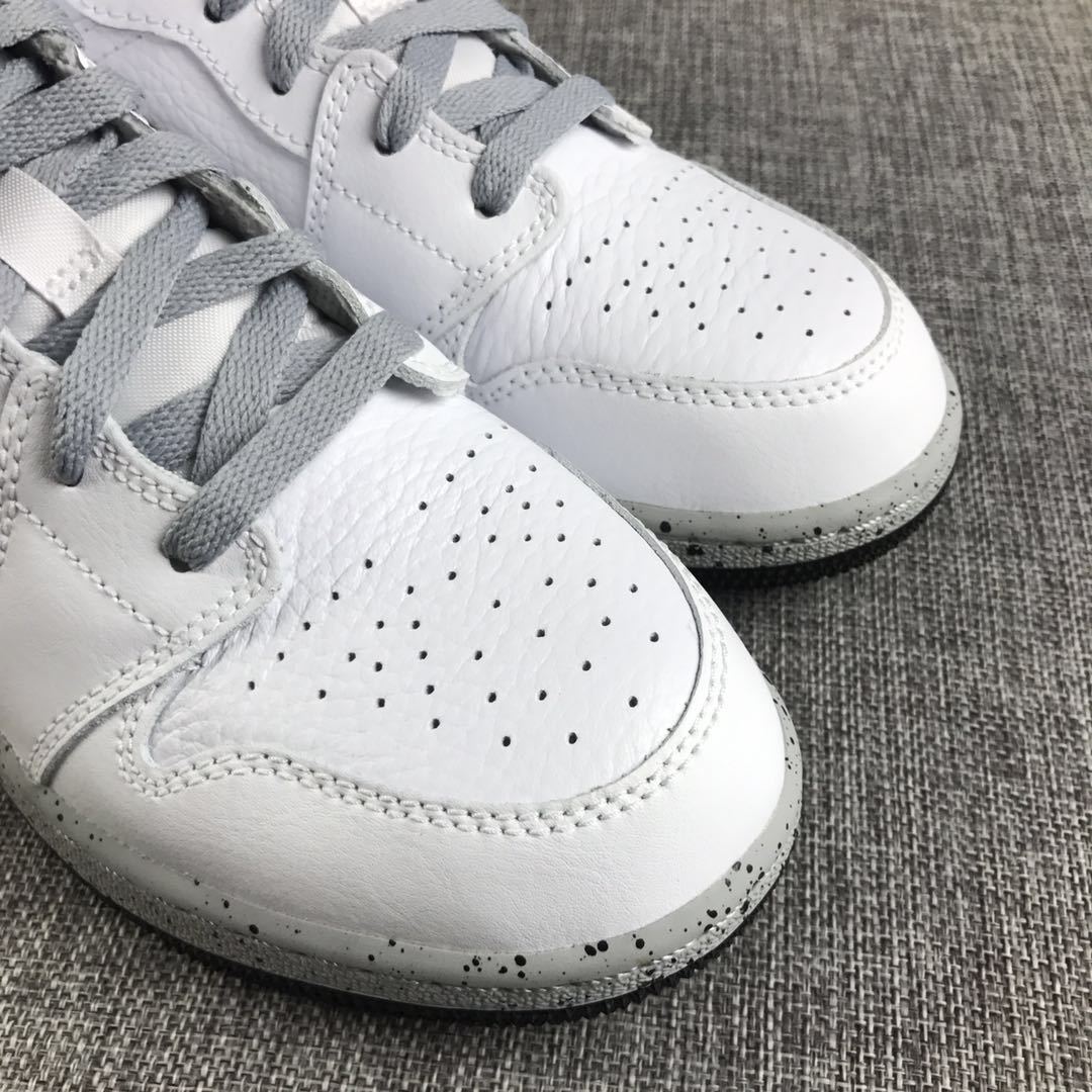 Close-up of the white perforated toe boxes, grey laces, stitching, and speckled midsole.