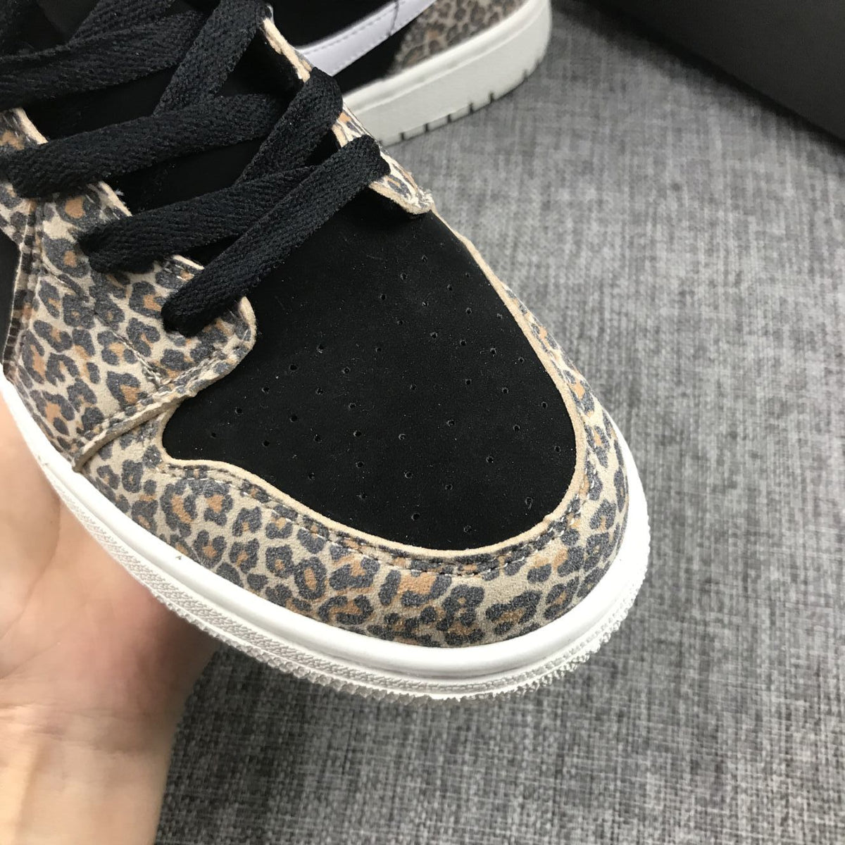 Close-up of the black perforated toe box, black laces, and leopard-print eyestay and toe overlay.