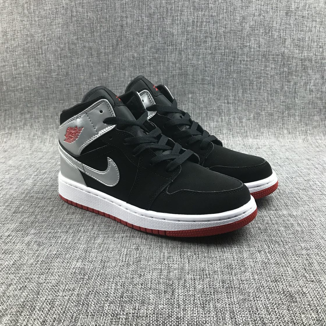 Three-quarter view of the black and silver sneaker pair with red outsole edges.