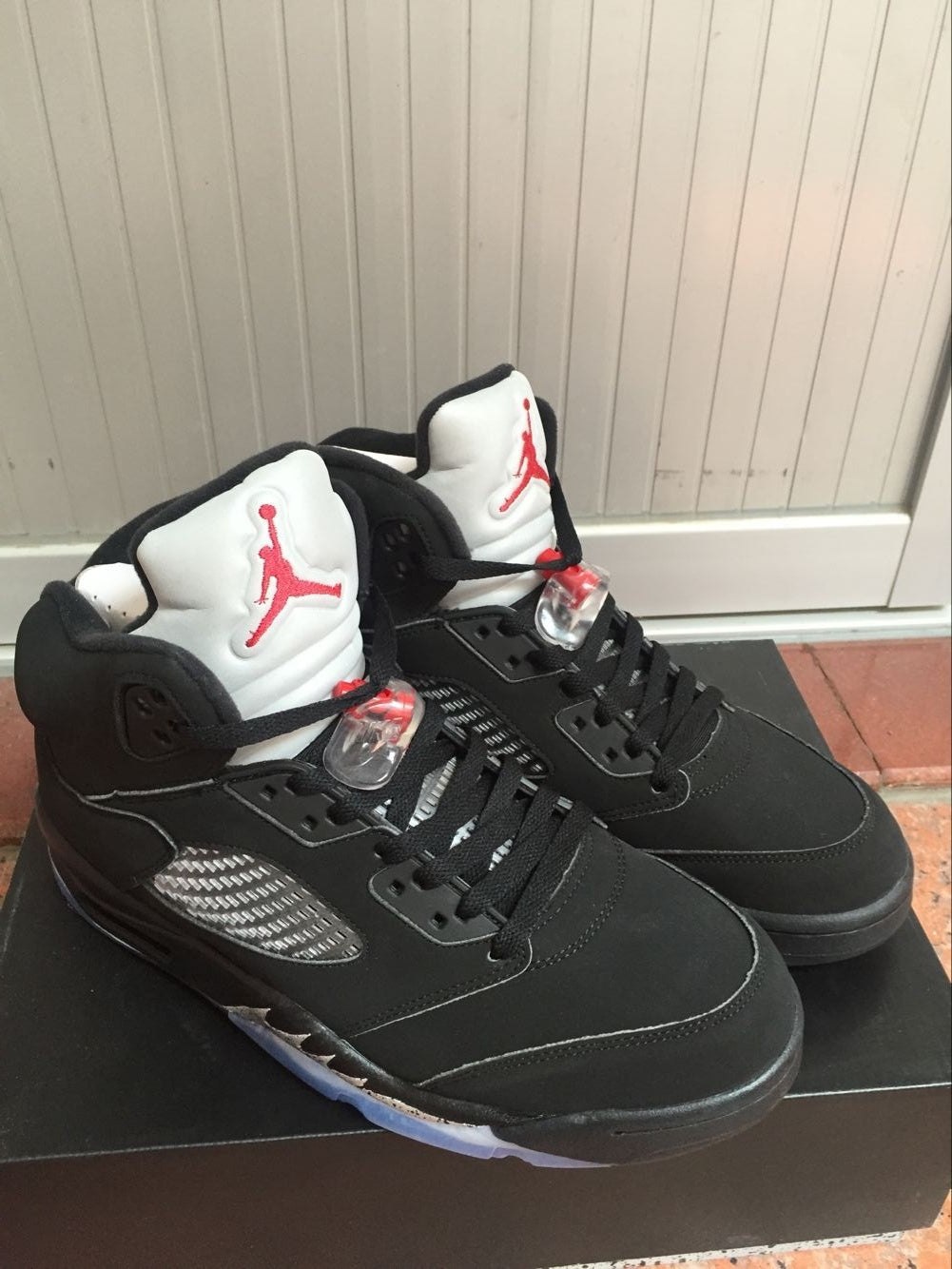 Pair of black high-top sneakers viewed from above, showing white tongues with red Jordan graphics.
