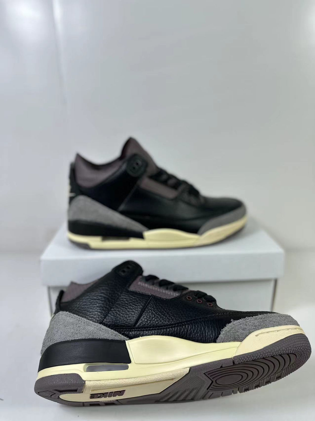 Angled view highlighting the black upper, gray overlays, cream midsole, and outsole tread.