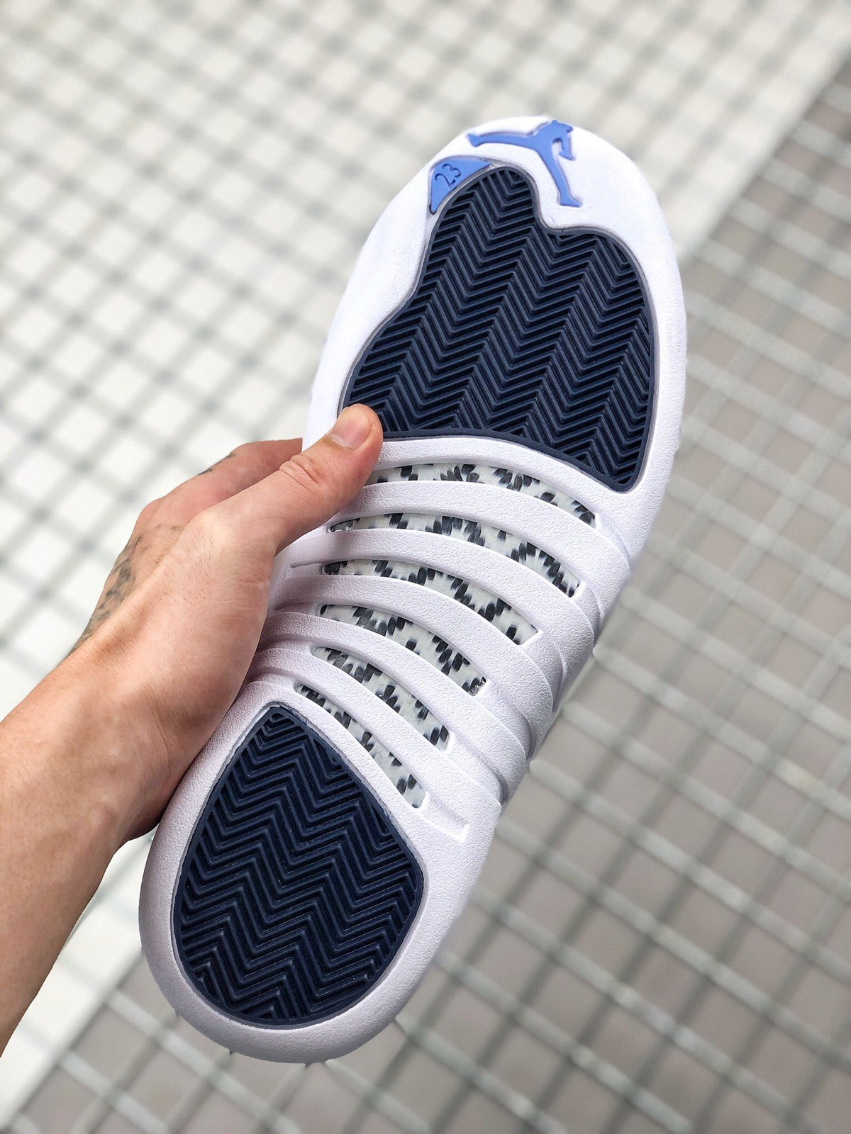 Bottom view of the sneaker showing dark blue herringbone-style outsole sections and white surrounding rubber.