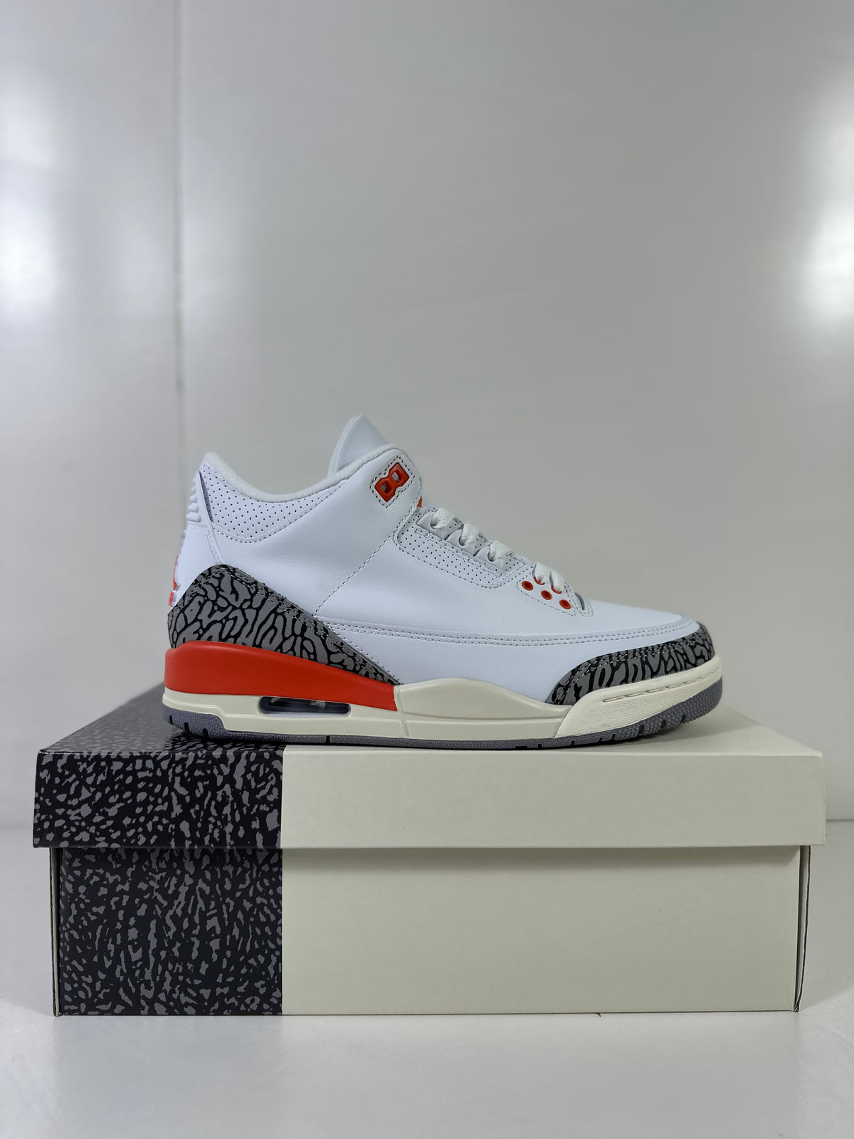 Side profile of the white and grey high-top sneaker with red heel detailing and a visible heel air window.