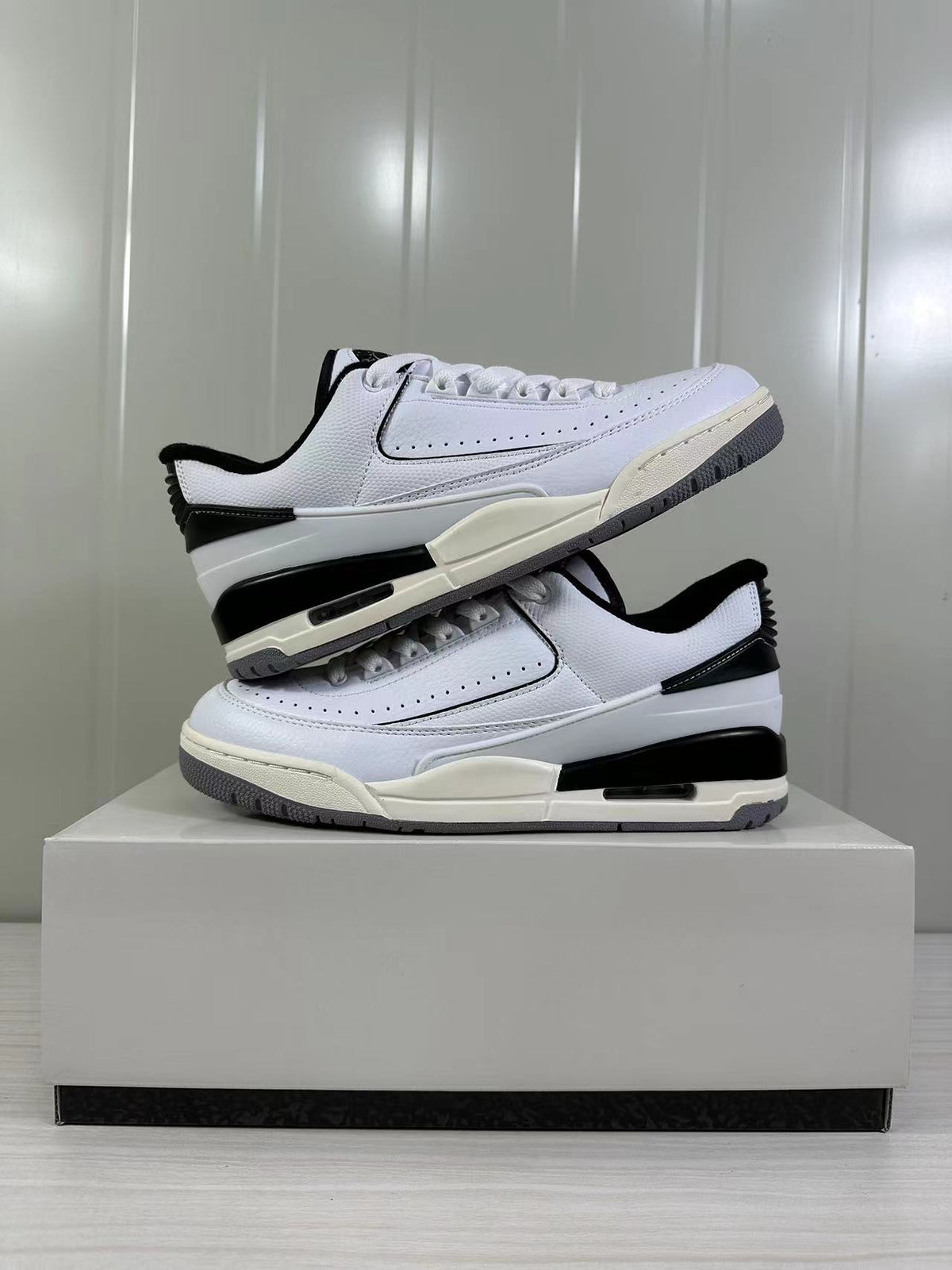 Side profile of the paired sneakers highlighting the white upper, black midsole section, and low-top shape.