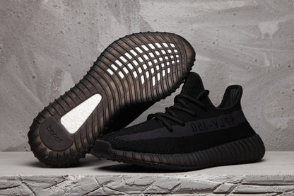 Black Yeezy 350 V2 sneakers shown from the side and sole, highlighting the ribbed outsole and tonal SPLY-350 stripe.