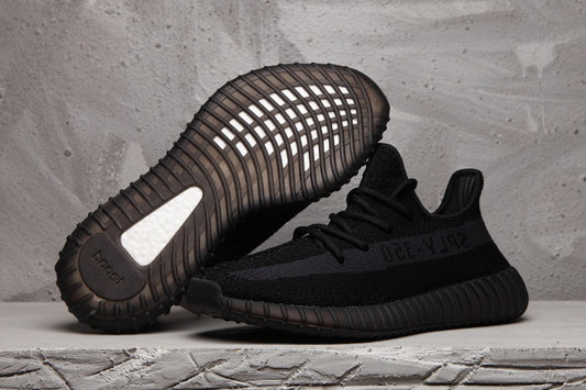 Black Yeezy 350 V2 sneakers shown from the side and sole, highlighting the ribbed outsole and tonal SPLY-350 stripe.