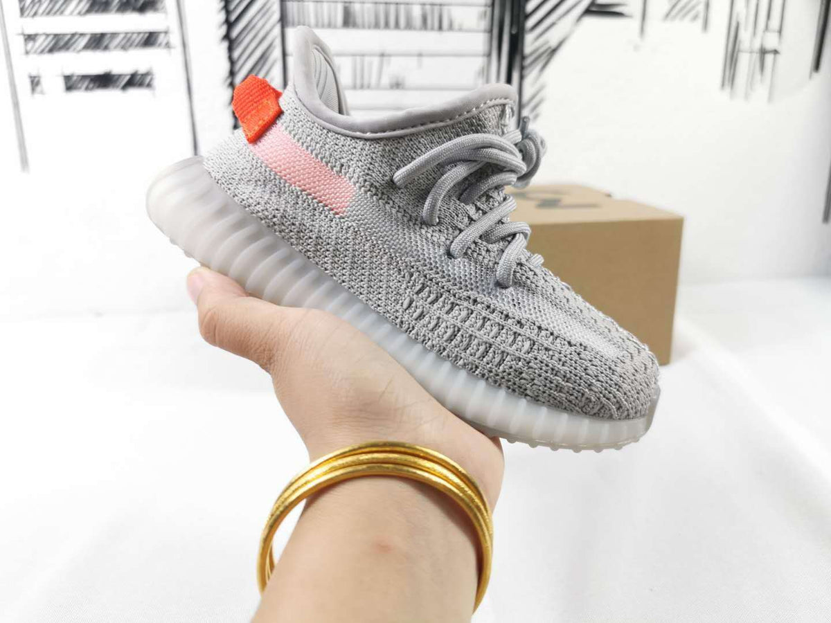 Side profile of the gray sneaker with pink stripe, orange heel accent, and translucent sole.