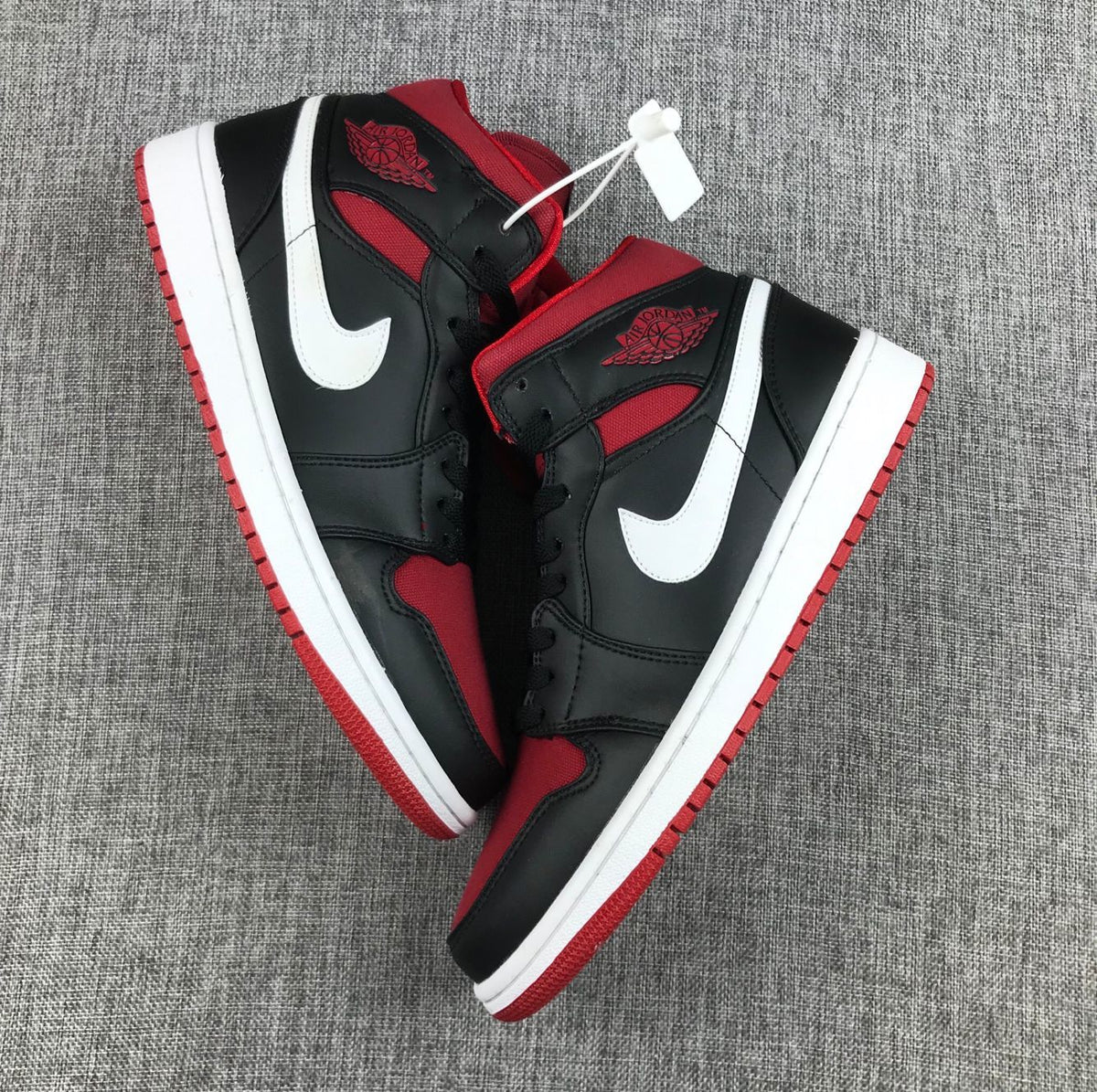 Overhead view of the matching pair showing black uppers, red panels, white Swooshes, and red outsoles.