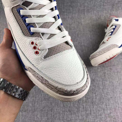 Close-up of the white textured upper, grey perforated tongue area, blue lace supports, and patterned toe panel.