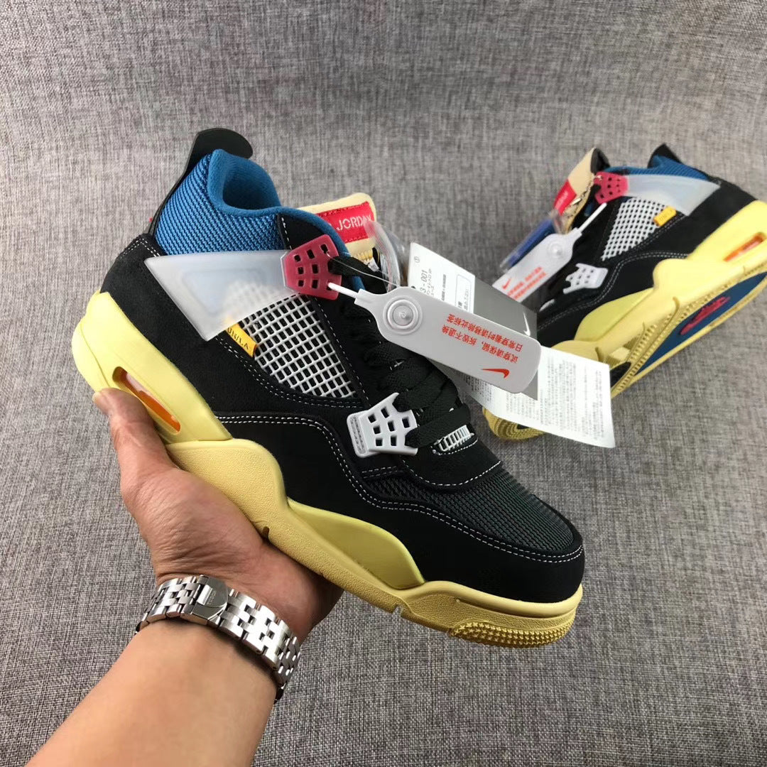 Handheld side view of a black sneaker showing the white mesh panel, translucent side piece, red hardware, and yellow-toned sole.