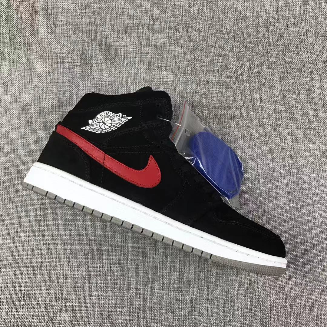 Single black Jordan 1 Mid sneaker with red Swoosh, wing branding, and a packaged blue lace bundle.