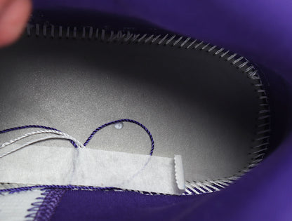 Close-up of the purple shoe interior, stitching and loose lace ends.