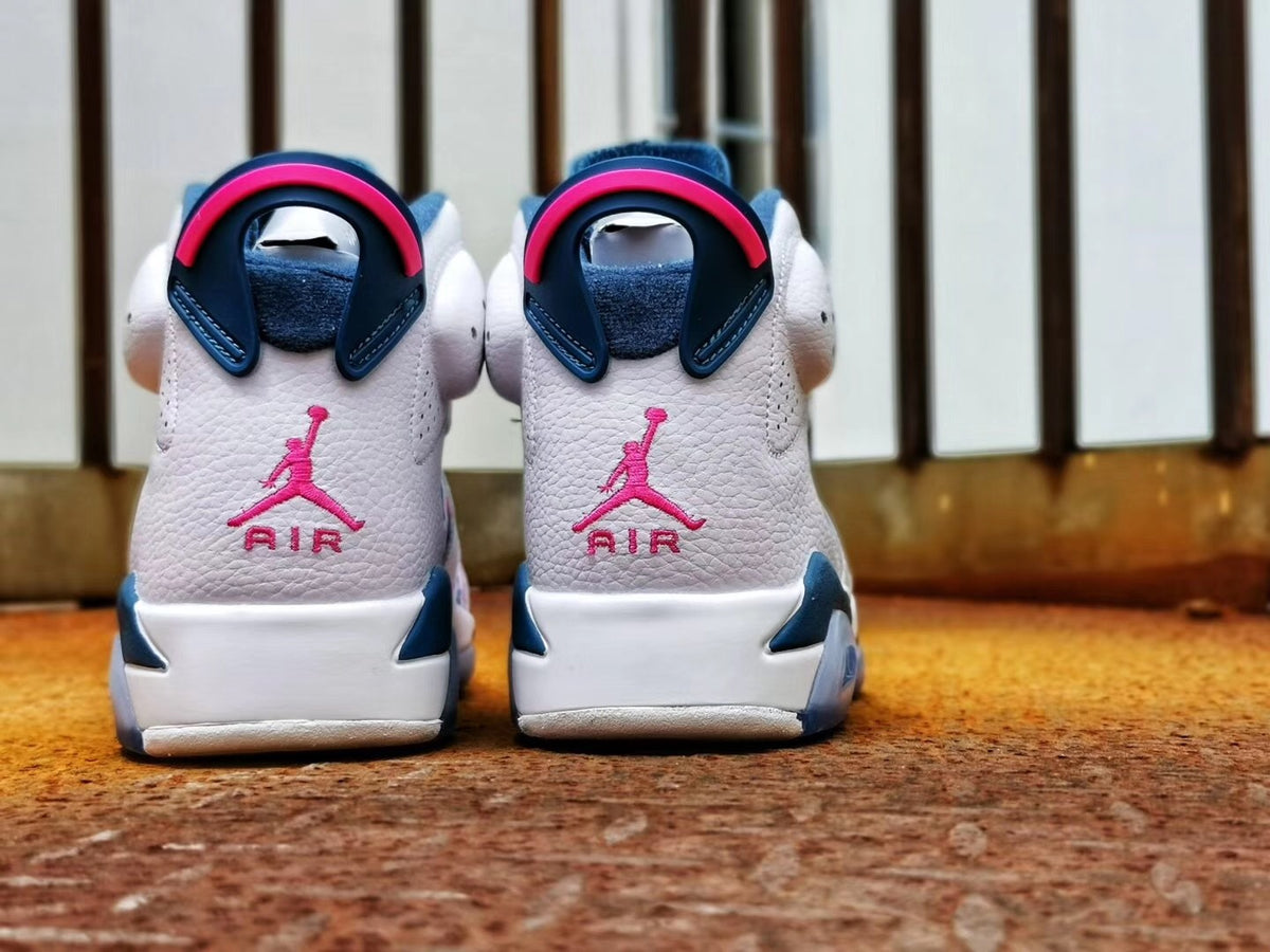 Rear view of the sneakers showing pink Jordan branding, white heels, and dark blue and pink pull tabs.