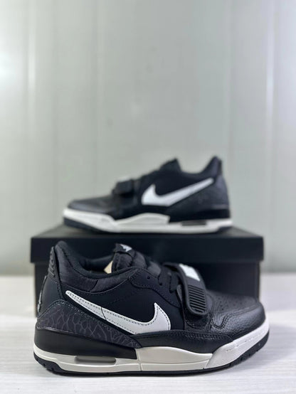Angled side view highlighting the white side detailing, textured heel panel, strap, and layered black and white midsole.