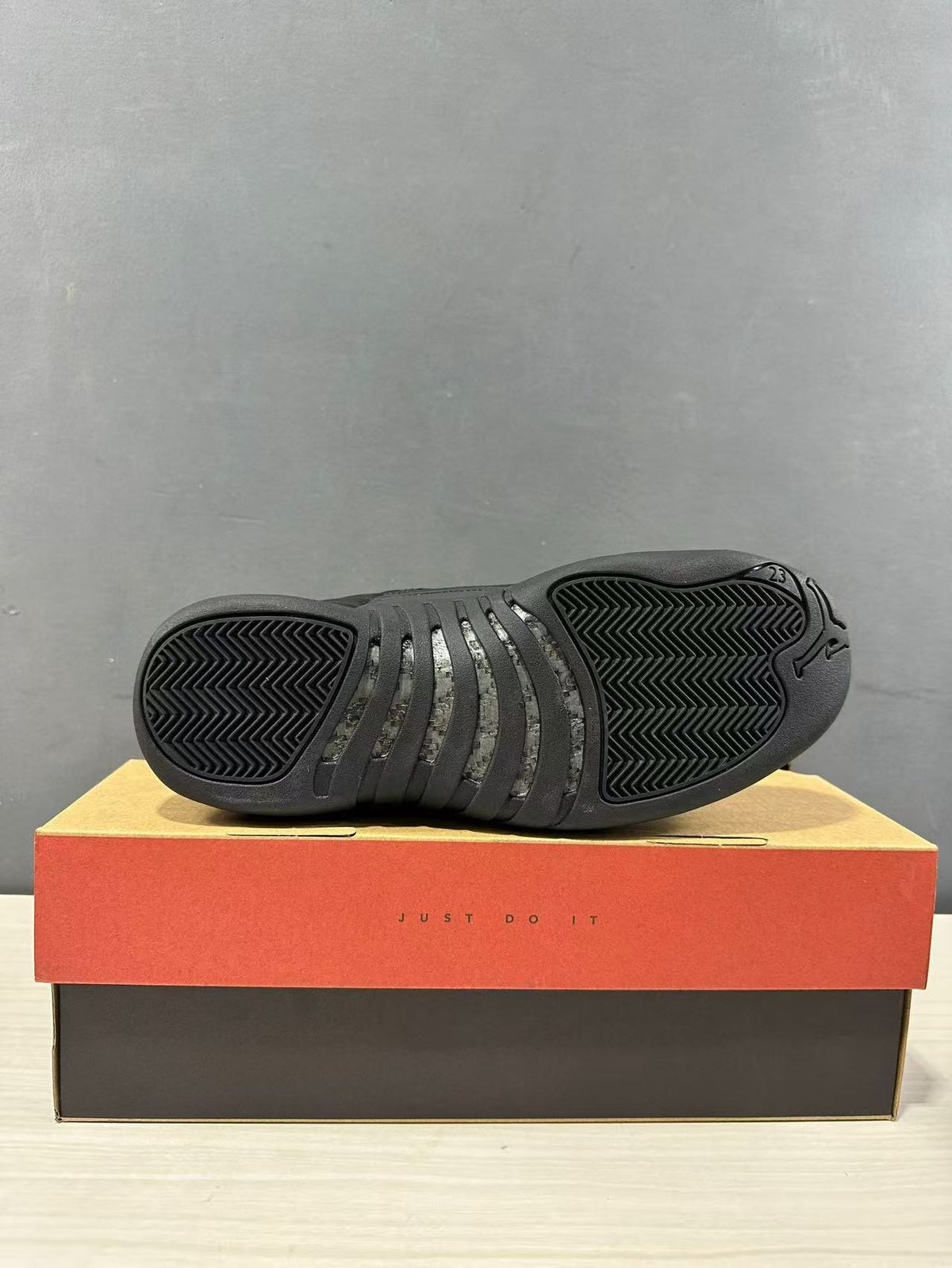 Bottom view of the black sneaker showing segmented herringbone-style outsole tread.