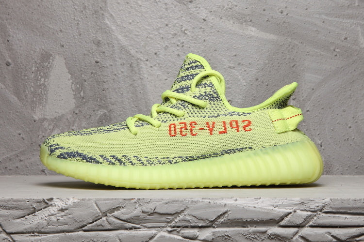 Side profile of a lime green knit sneaker with contrasting red side text.