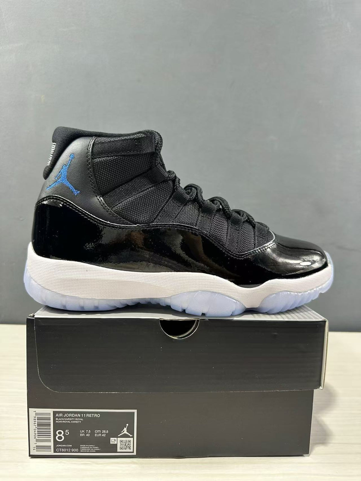 Side view of a black and blue Jordan Air Jordan 11 high-top sneaker displayed on its shoebox; the box label shows size 8.5, EU 42, and style code CT8012 900.