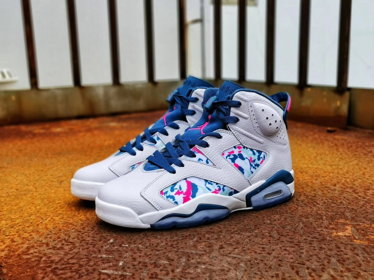 Pair of multicolor Air Jordan 6 sneakers shown from a front three-quarter angle on a floor.
