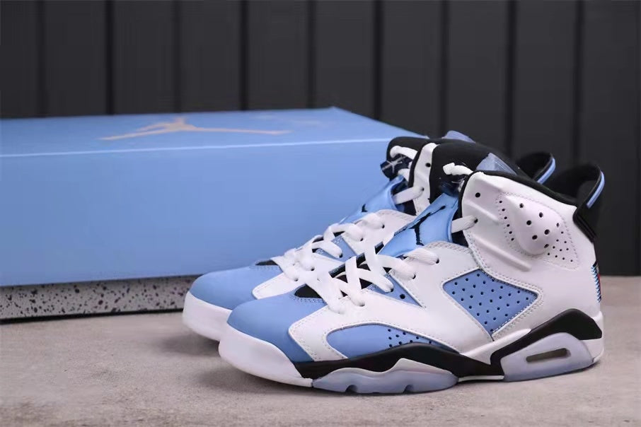 Pair of white, University Blue, and black Jordan 6 high-top sneakers shown from a front three-quarter angle.
