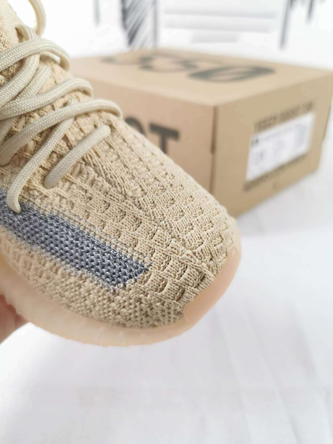 Close-up of the linen-yellow knit-style toe, laces, gray side stripe, and translucent sole.