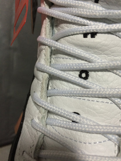 Close-up of the white laces and white textured upper with black stitched details.